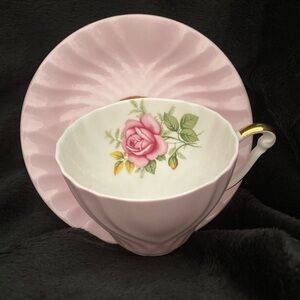 A vintage English bone china teacup and saucer with a pink rose design.